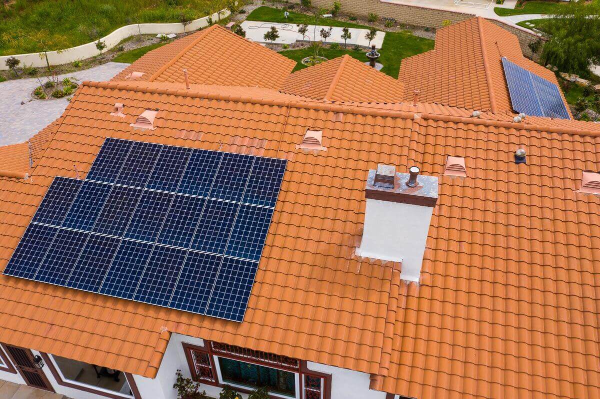 Solar panels installed on a terracotta tiled roof with a skylight ...